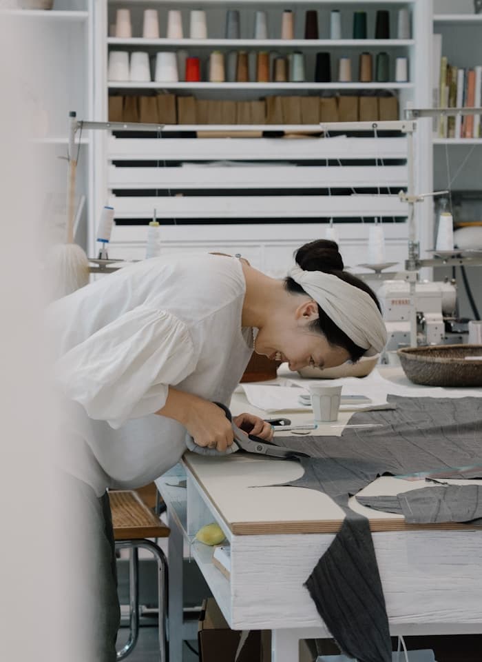 A maker at Babies Corner hand-cutting linen